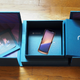A picture of an overly constructed blue box with the label "razer." A phone, that is clearly a render, is set in the center of the box. The box lies on a wood floor.
